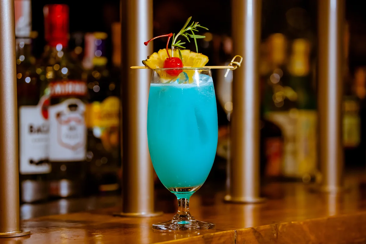 Glass of Blue Hawaii Cocktail on Wooden Bar Counter