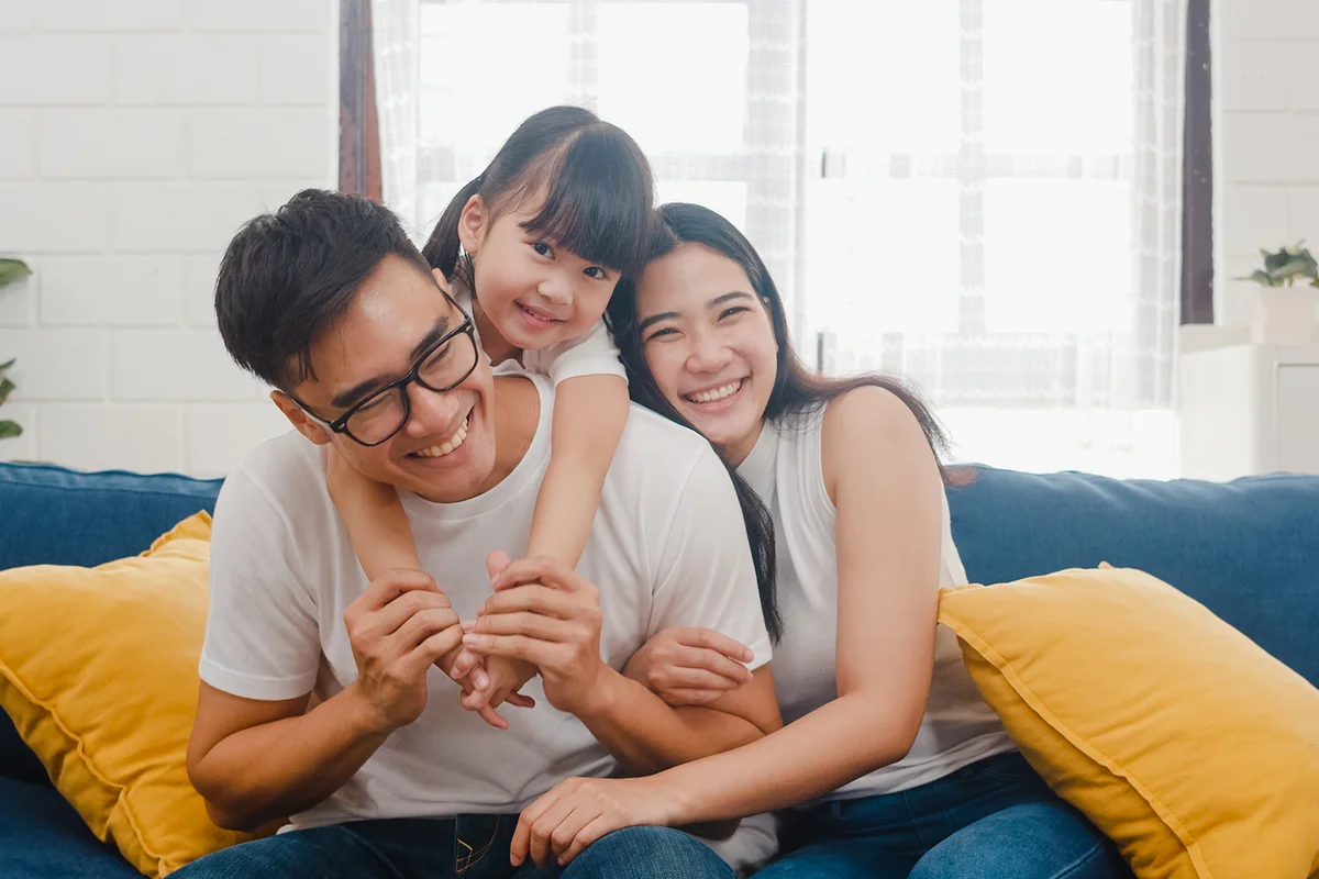 Happy cheerful family dad, mom and daughter having fun cuddling
