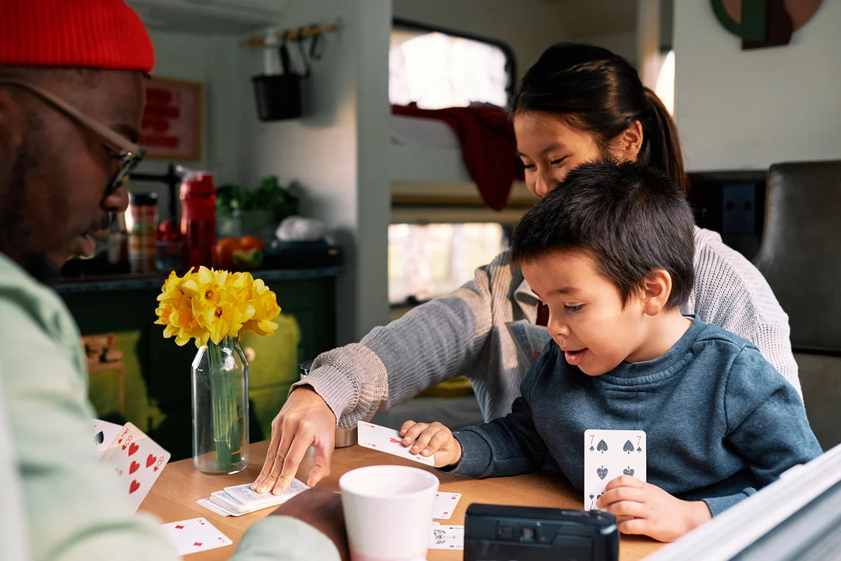 family sits together at the table in their motorhome and plays card games