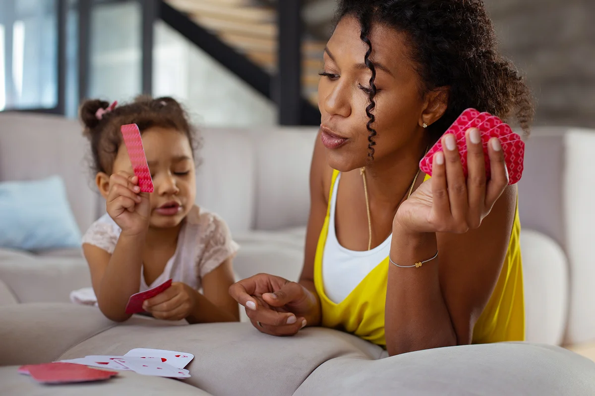 Attentive young woman looking at cards while playing with her kids