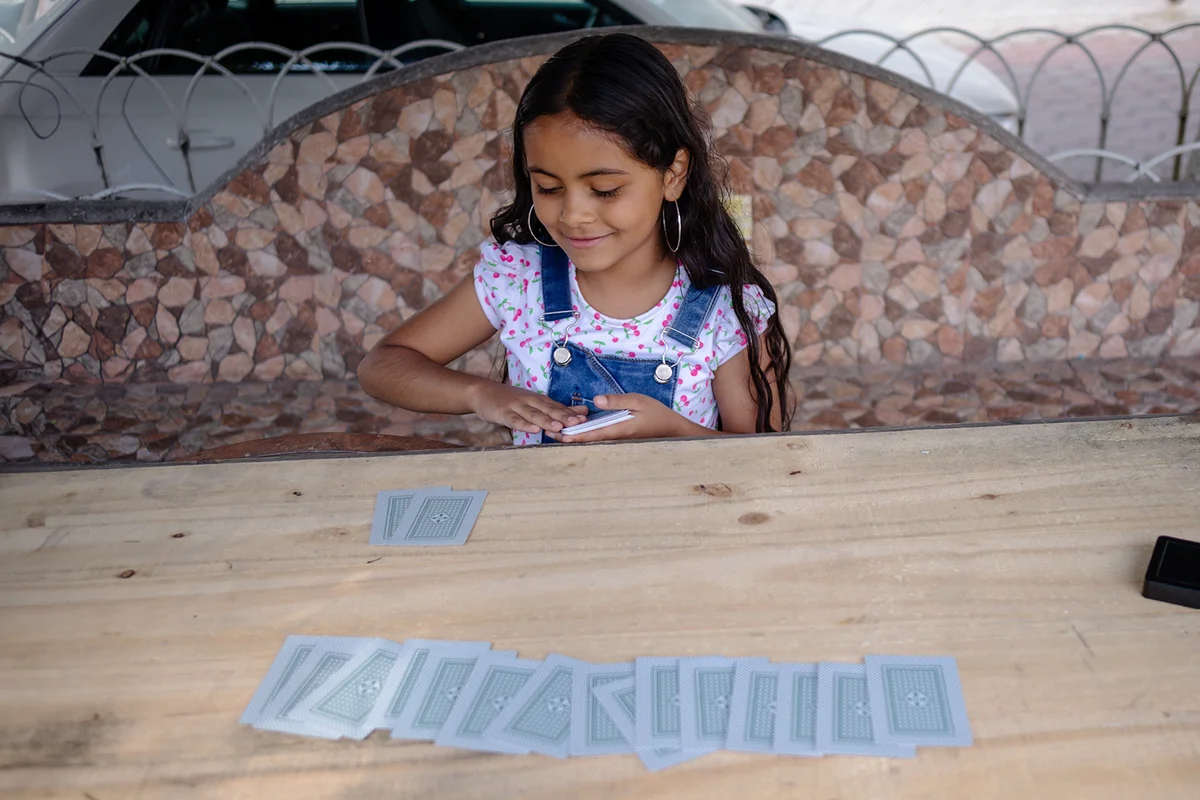 hispanic child girl playing making magic tricks with cards