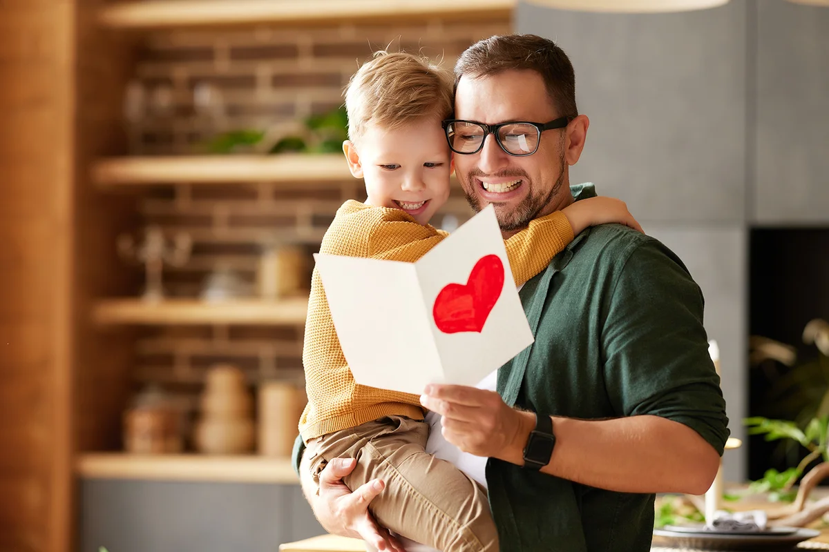 Portrait of happy family father with excited child son hugging smiling while celebrating Fathers day together at home.