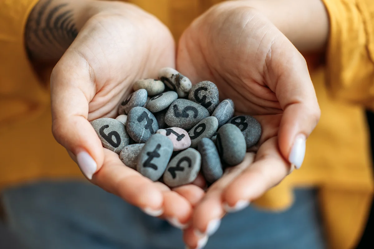 Many pebble stones with painted numbers in female palms