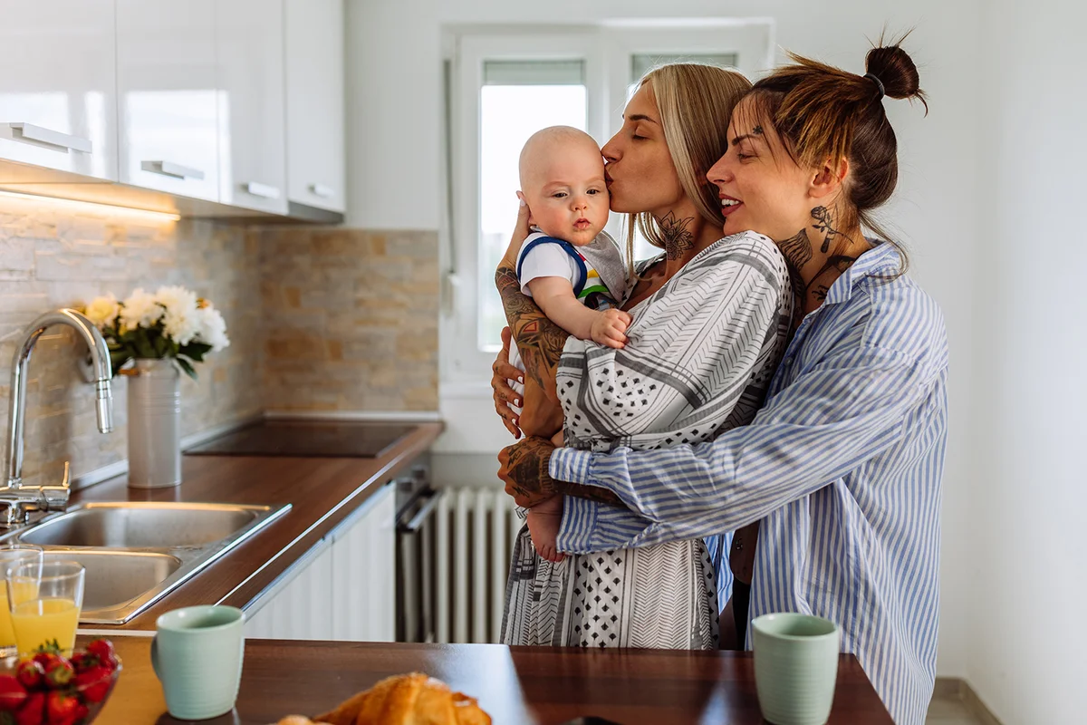 couple in pajamas hold their baby son and enjoying time spent together at home