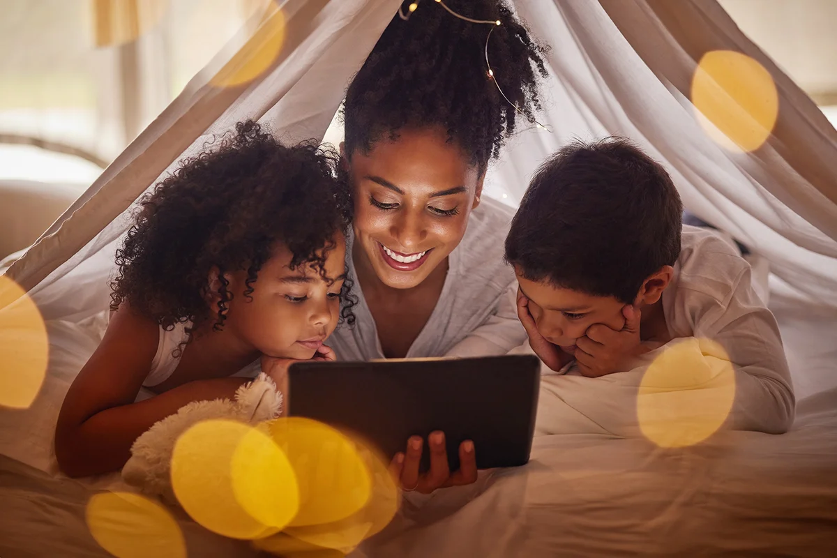 Family, children and tablet with a mother, girl and boy camping at home below a blanket in the bedroom.