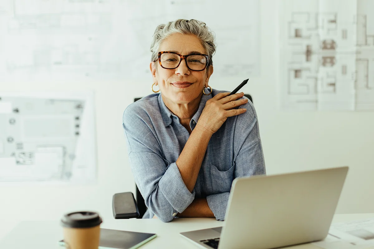 Mature female designer looks at the camera in her office, confident in her expertise and style of creativity.