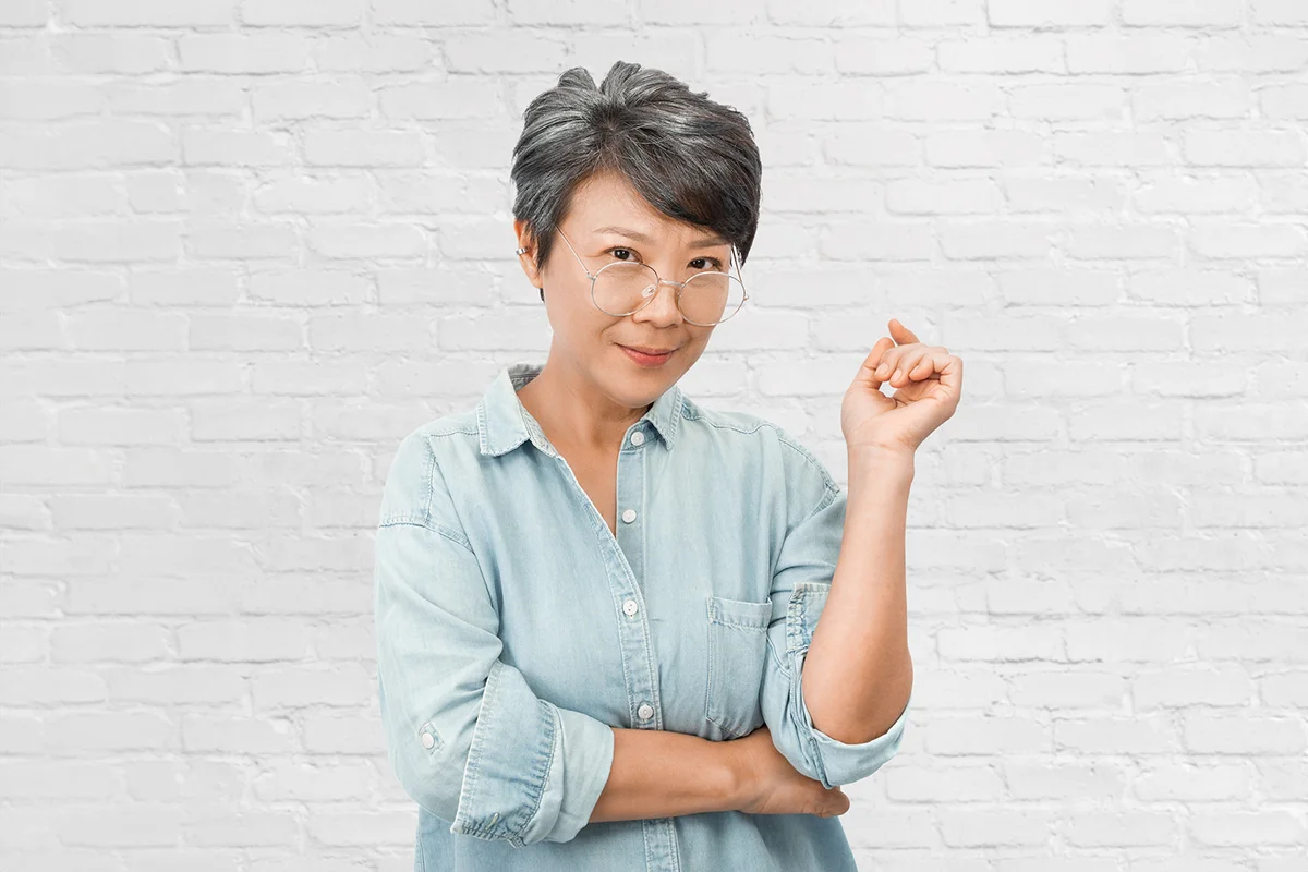 Beautiful old Asian woman with gray hair, wearing glasses and blue shirt
