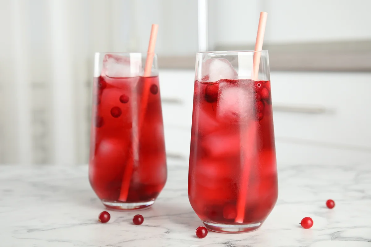 Tasty refreshing cranberry cocktail on white marble table indoors