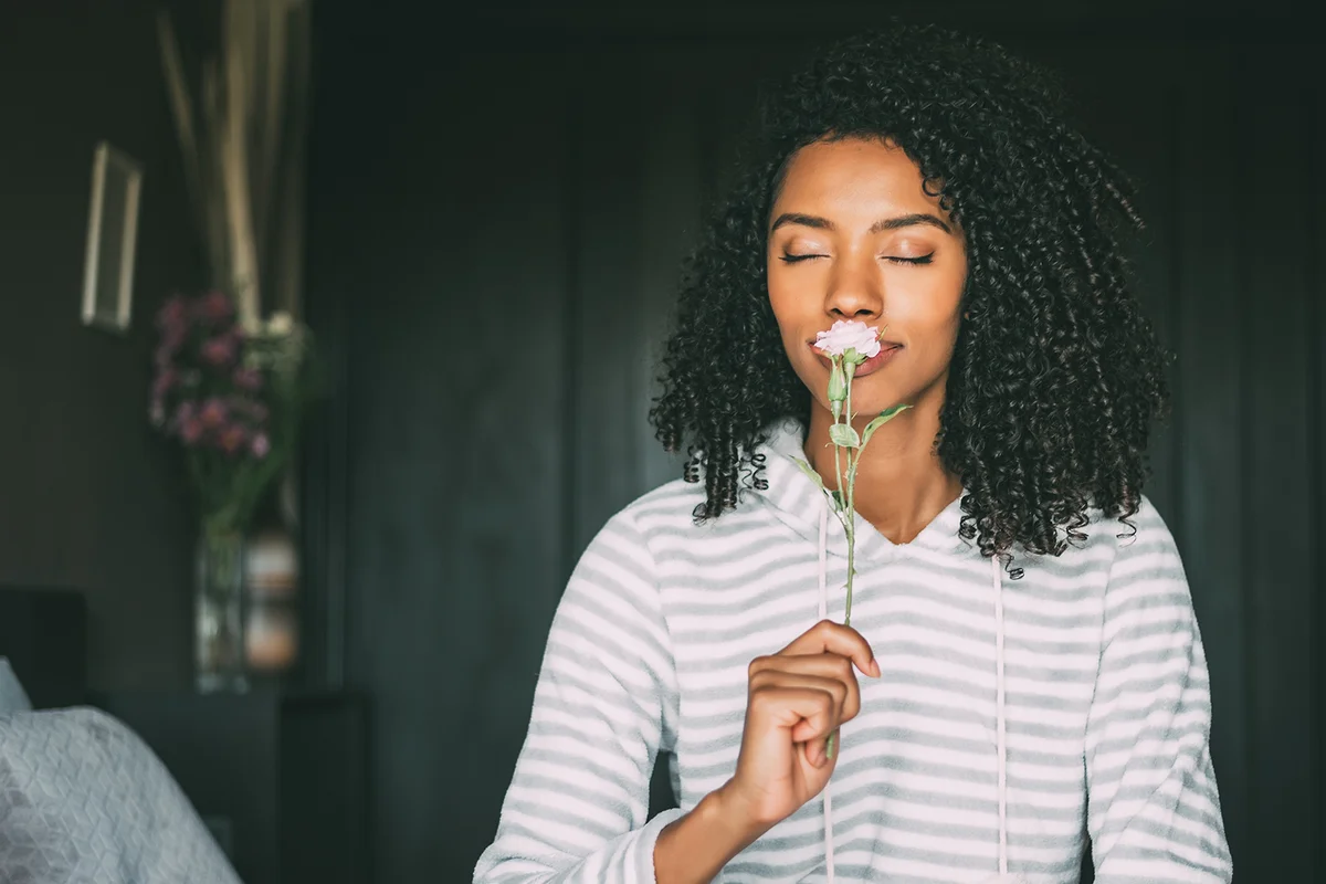 woman smelling a rose flower sit on bed