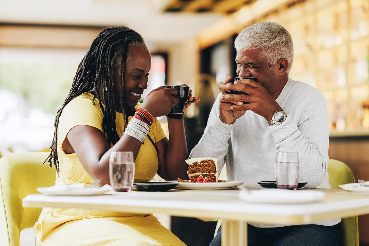 senior couple laughing together while having coffee in a cafe
