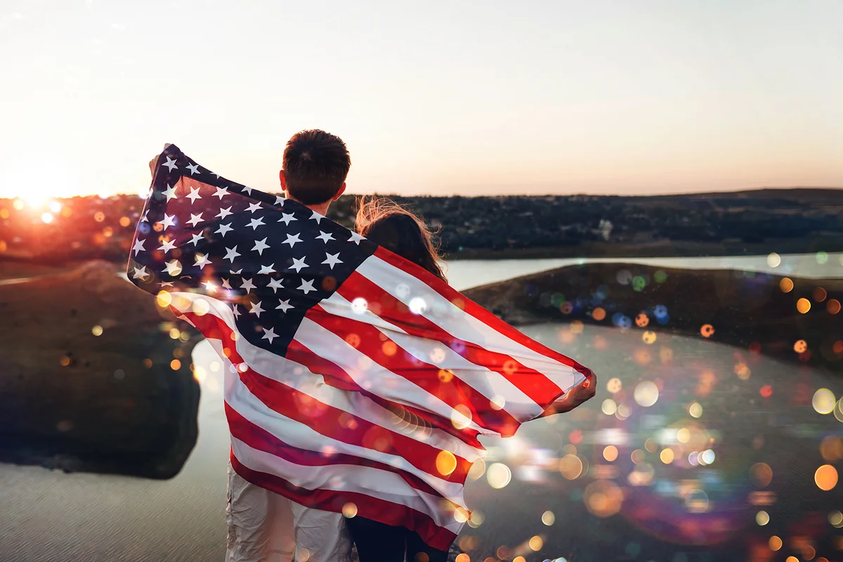 family with the American flag behind them at sunset