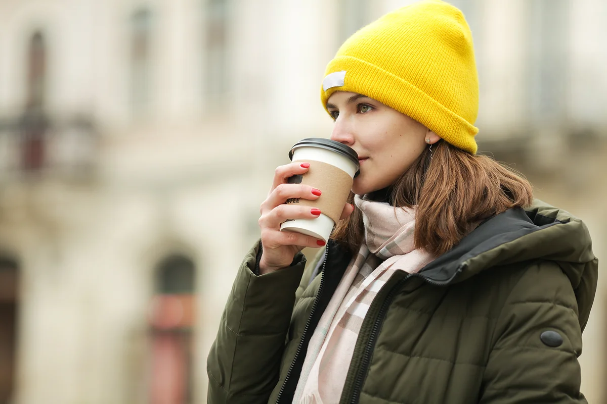 woman drinking hot beverage at street