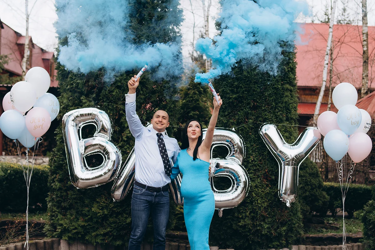 couple blowing up surprise balloon during gender reveal party
