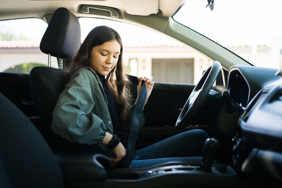 Teenage girl putting on her safety seatbelt