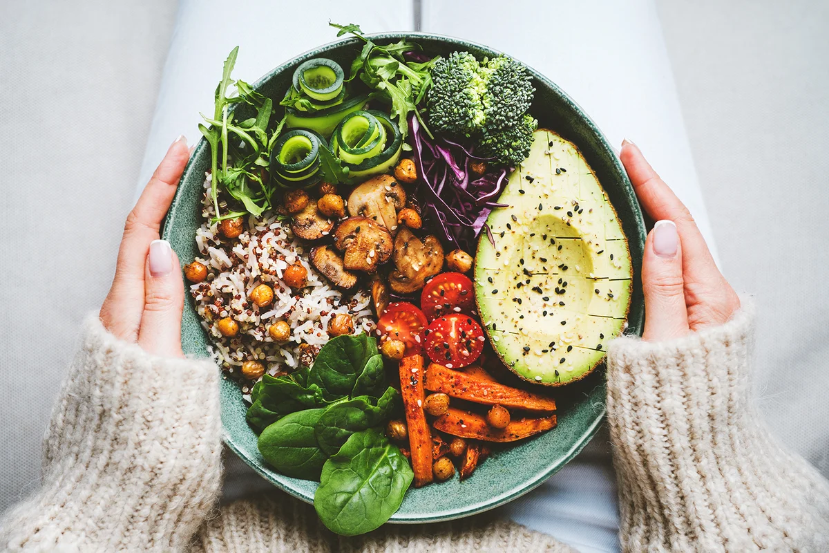 Woman holding plate with vegan or vegetarian food.