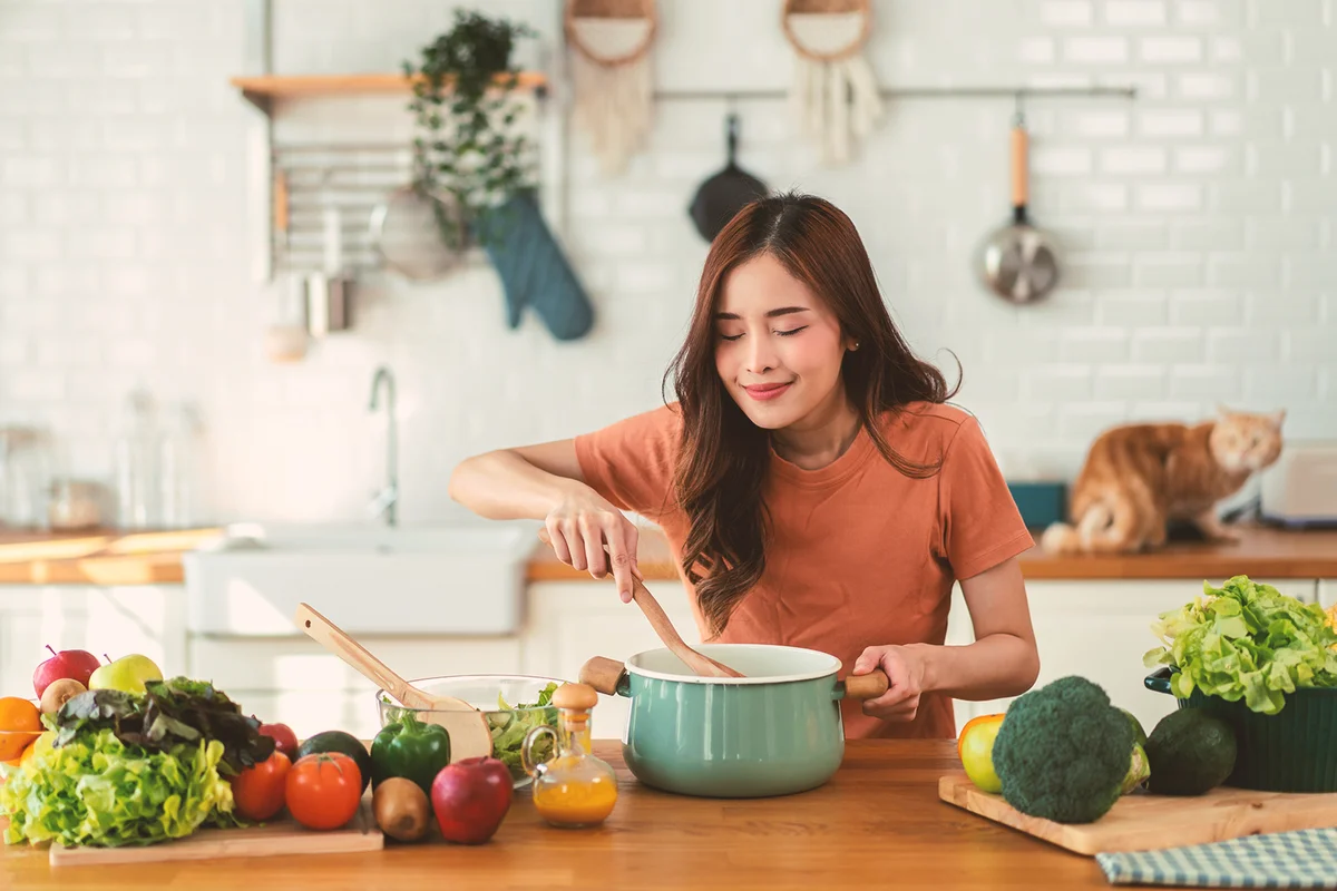 Young woman standing near stove and cooking, housewife, meal, chef, food