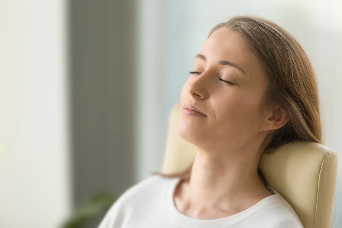 Relaxed woman lying on back chair with closed eyes.