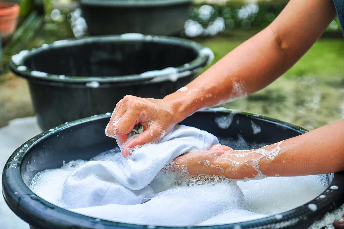 hands washing clothes in basin
