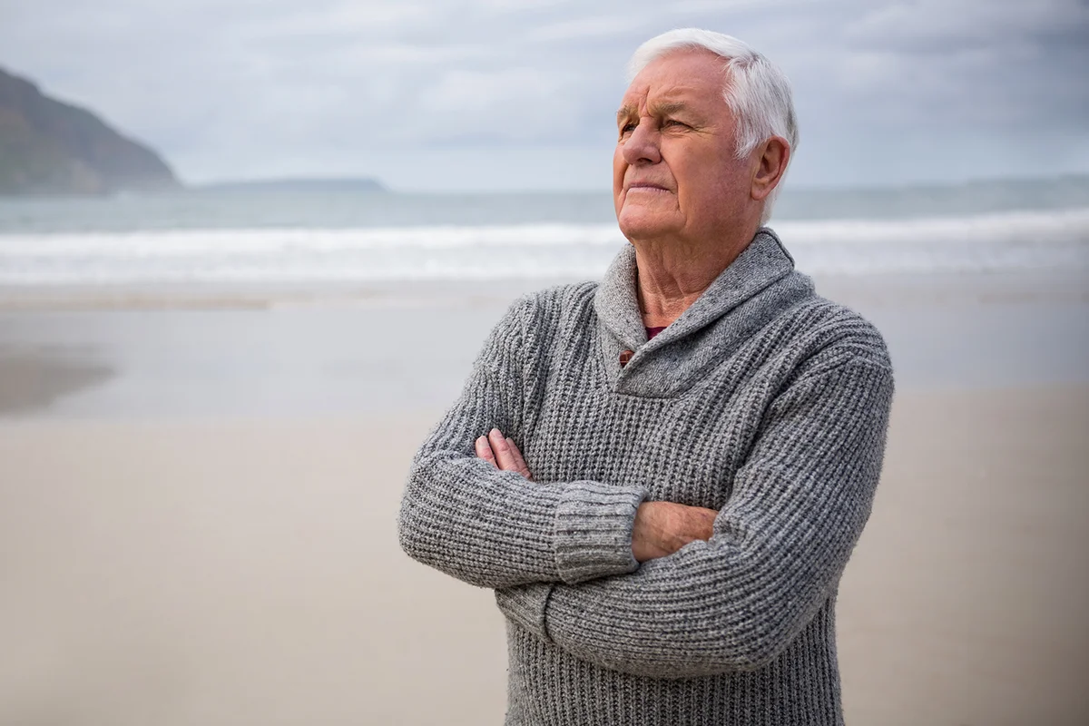 Thoughtful senior man standing at the beach