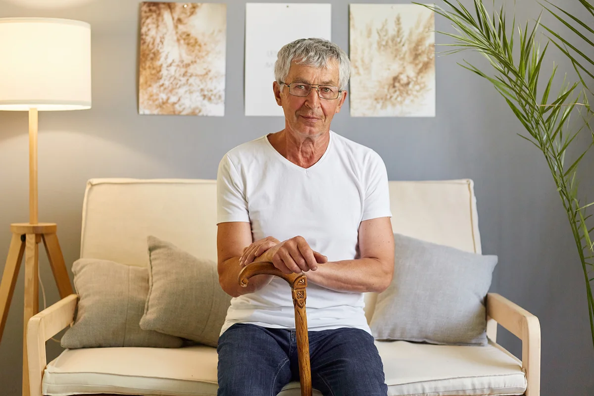 Calm relaxed man pensioner wearing white T-shirt and jeans sitting on sofa