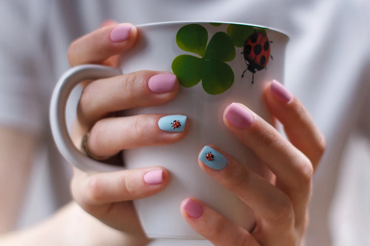 Girlish manicure with volumetric ladybugs on pink and blue fingernails.