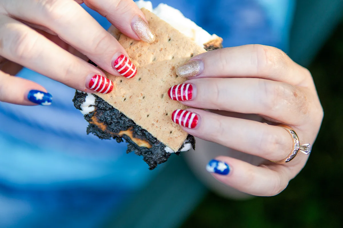 woman holds a s'more with patriotic nails