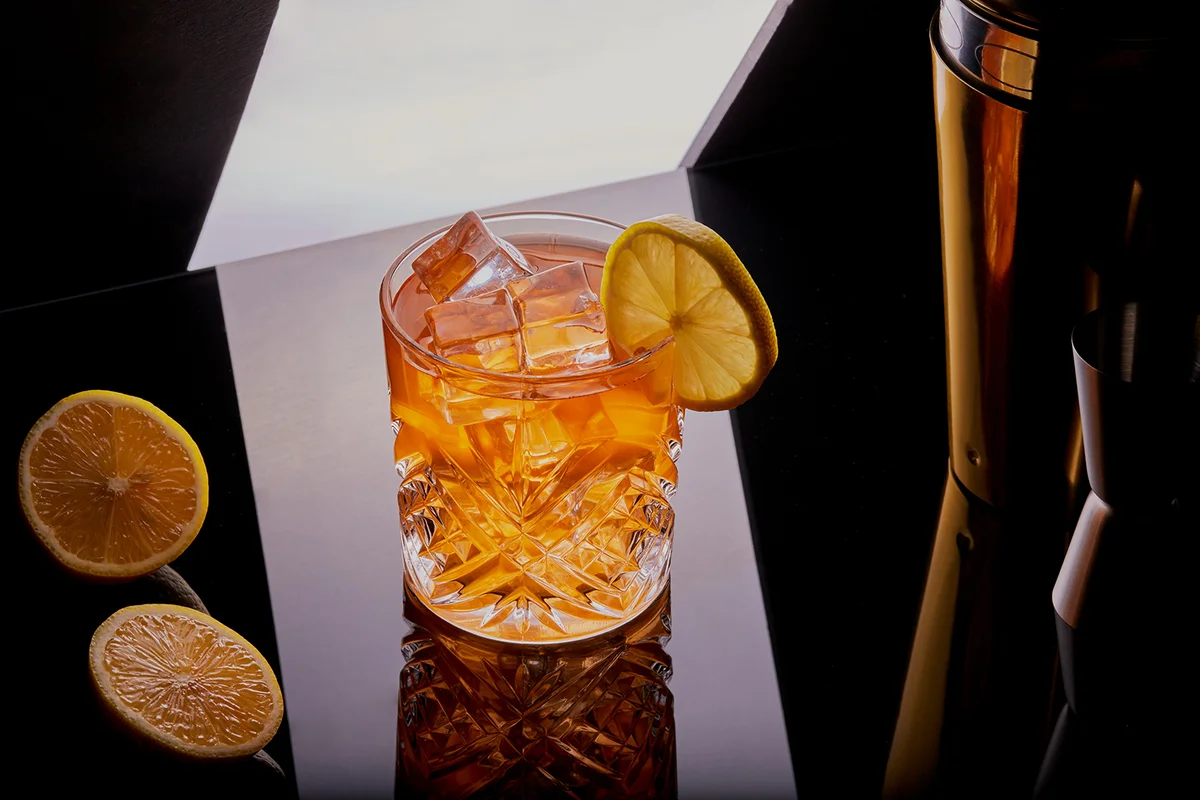 Cocktail garnished with a lemon slice with cocktail shaker
