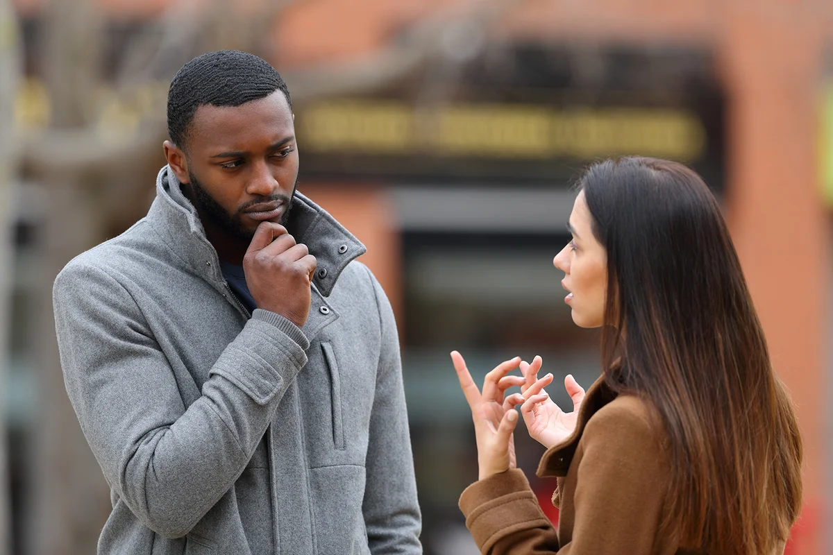 Suspicious man listening a woman talking in winter in the street