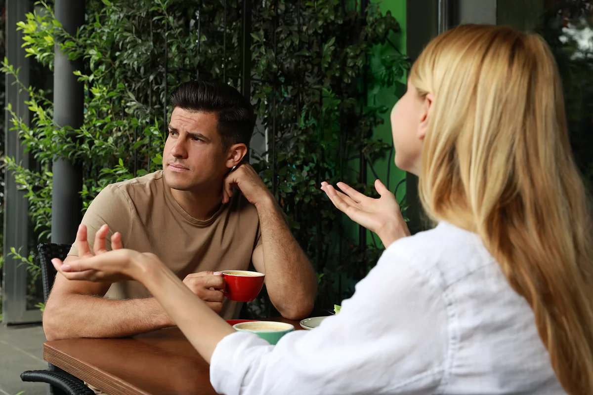 Man having boring date with talkative woman in outdoor cafe