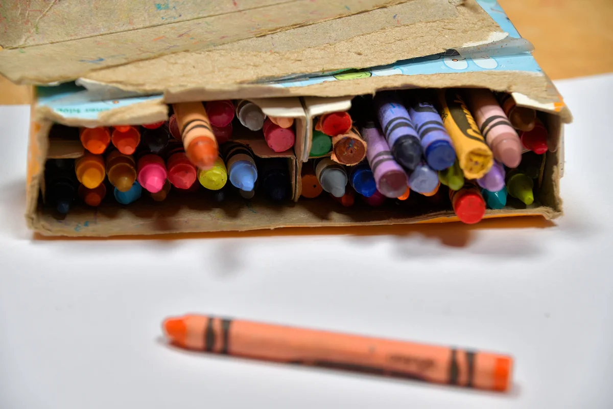 Tattered old box of worn Crayola crayons of 64 colors in soft focus.