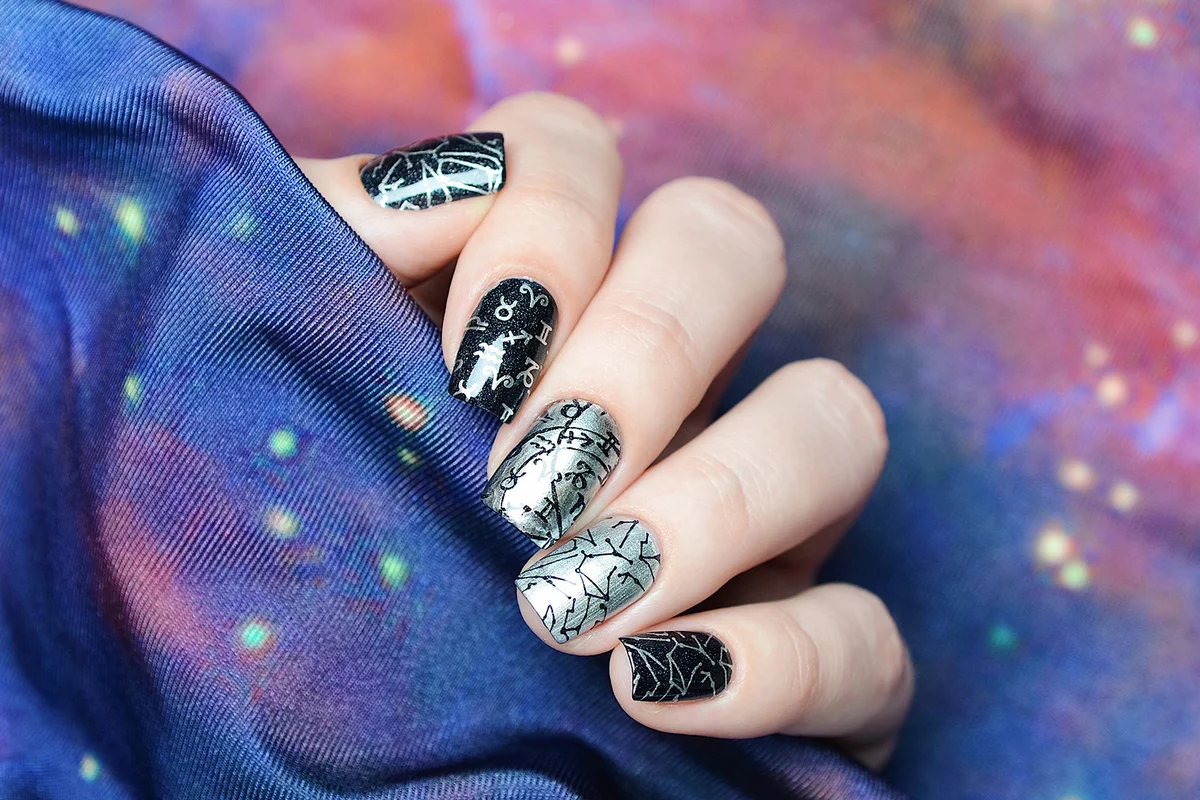black and gray manicure with a pattern of the starry sky on a cosmic background