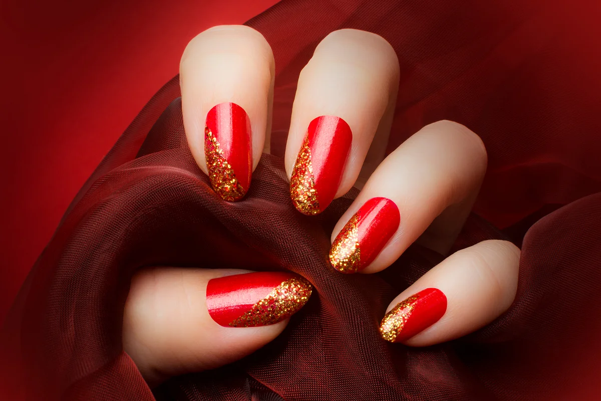 Female hand with beautiful red and golden glittered nails