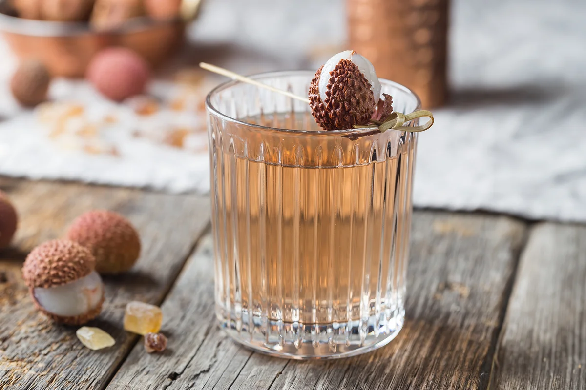 Glass of cold lychee juice on the old wooden table, rustic style