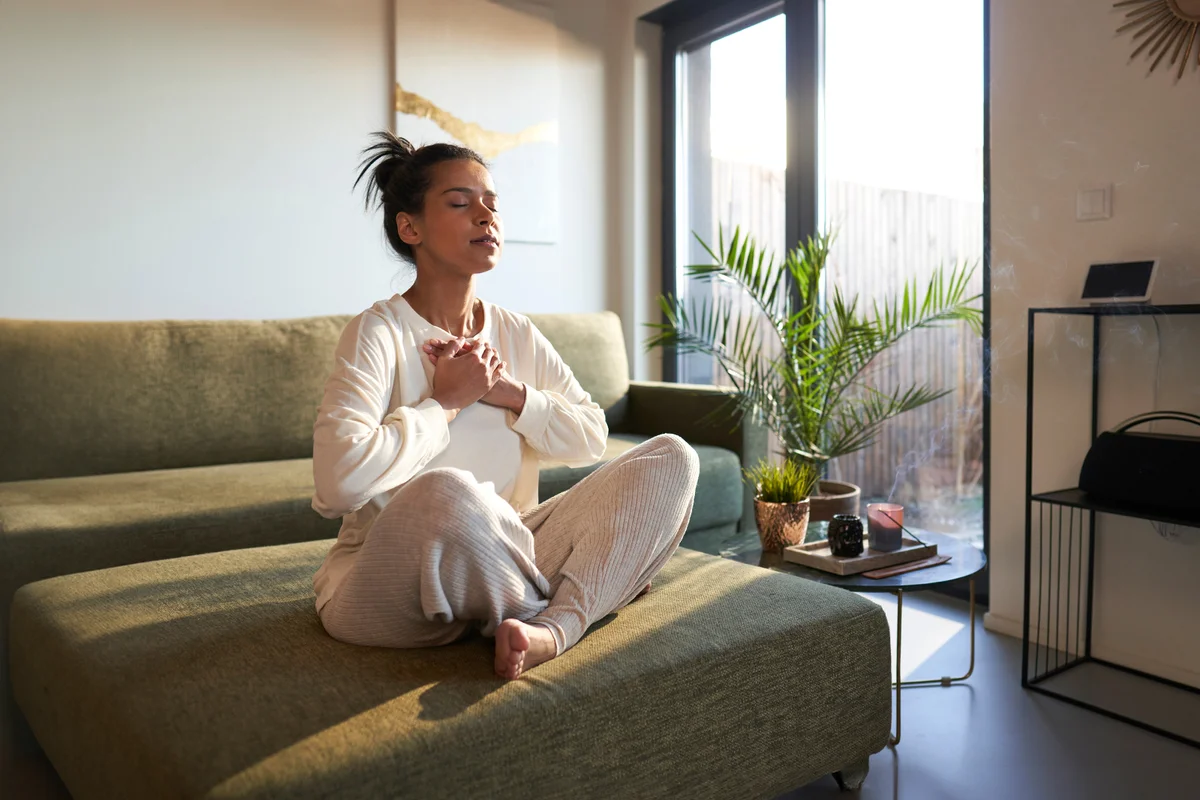 Woman meditating at home with eyes closed