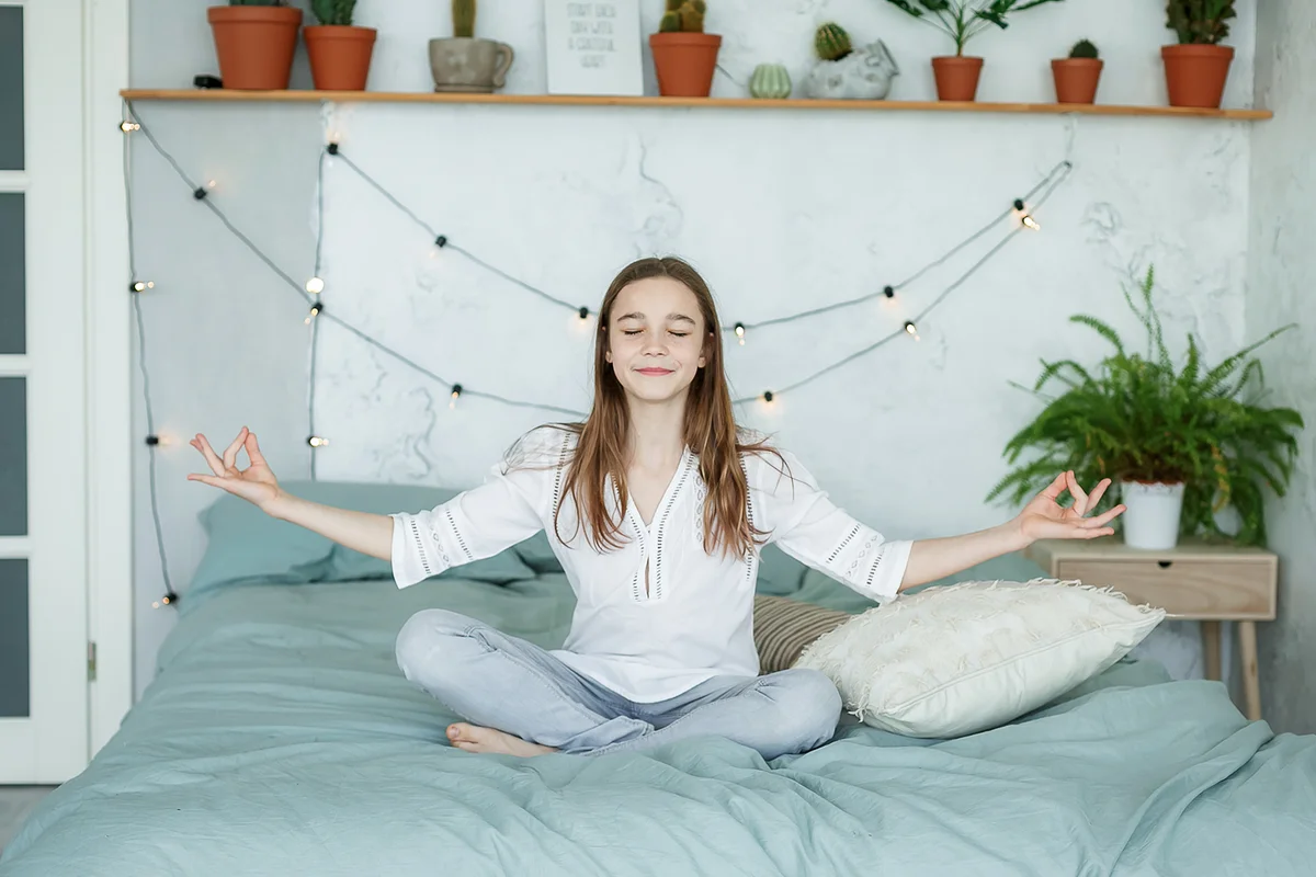 Teen-girl doing yoga in lotus pose at home