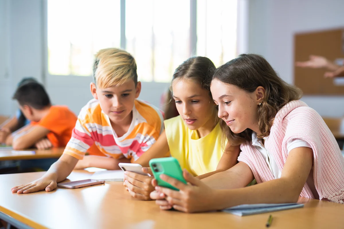 Group of kids using smartphones during lesson in school.