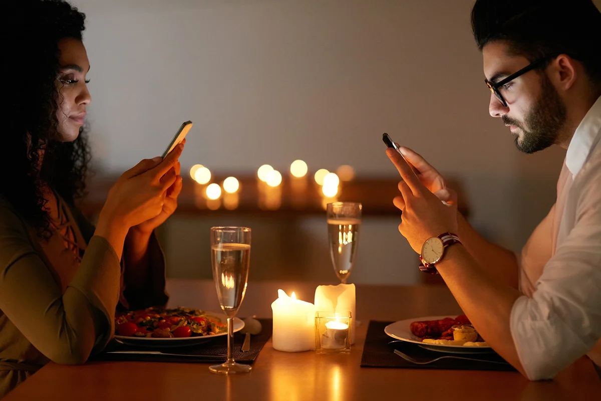 young couple texting on their phones while out for dinner.