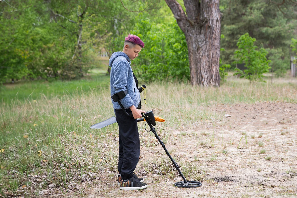 boy is looking for valuables with a metal detector