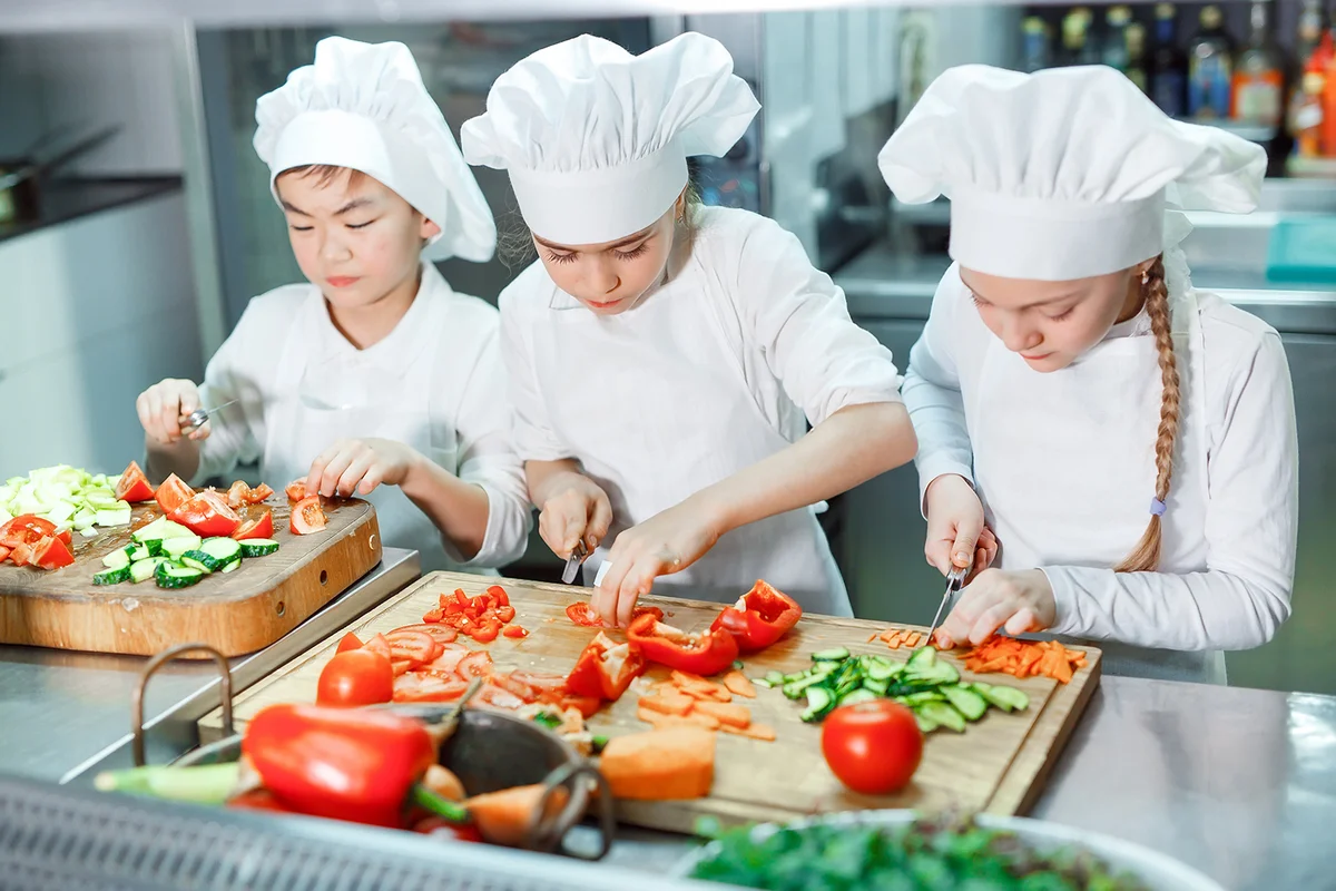Children grind vegetables in the kitchen