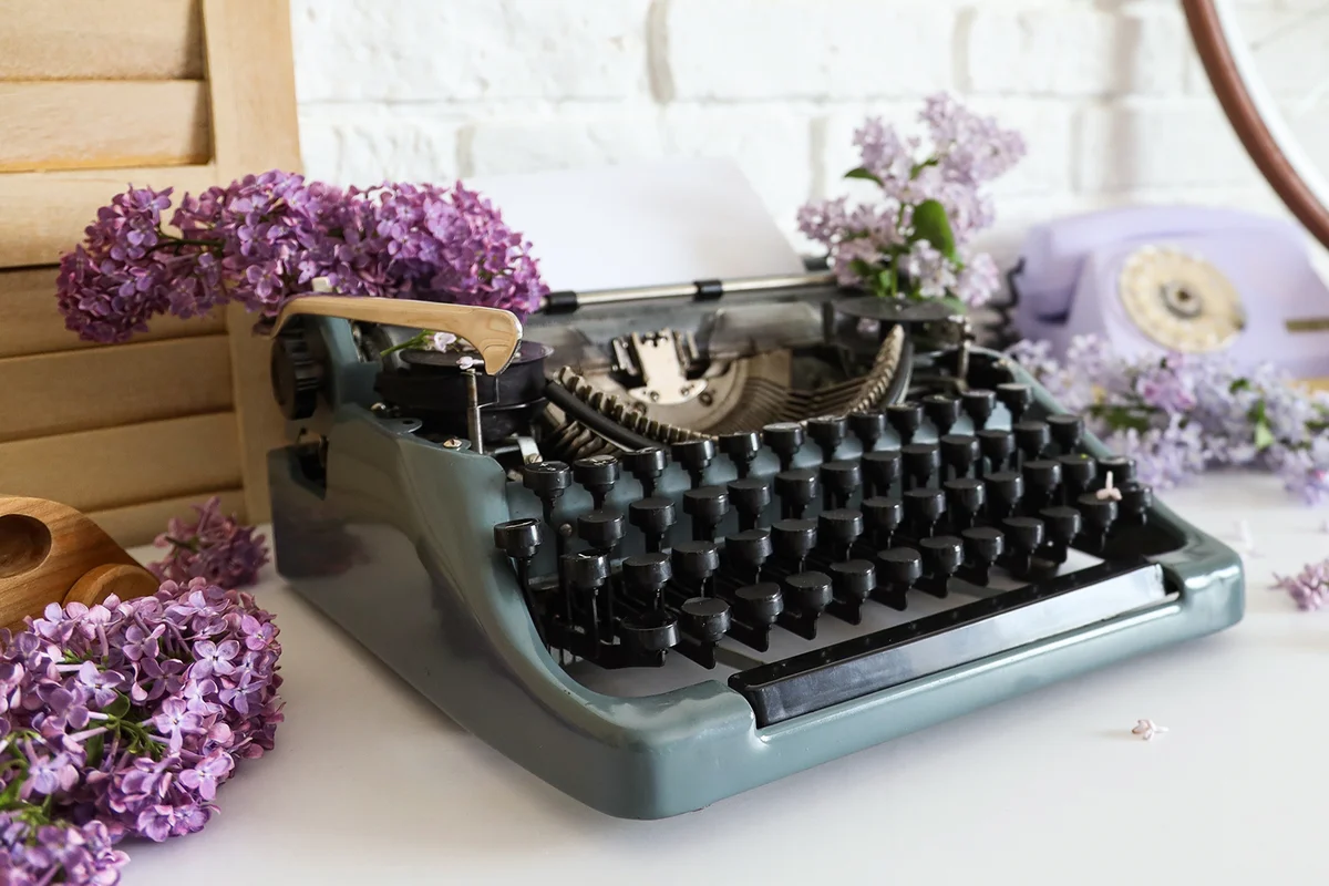 Vintage typewriter with lilac flowers on table in author's office