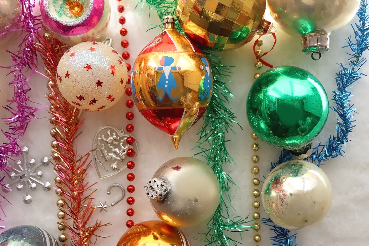 Colorful vintage Christmas ornaments and white faux fur blanket.