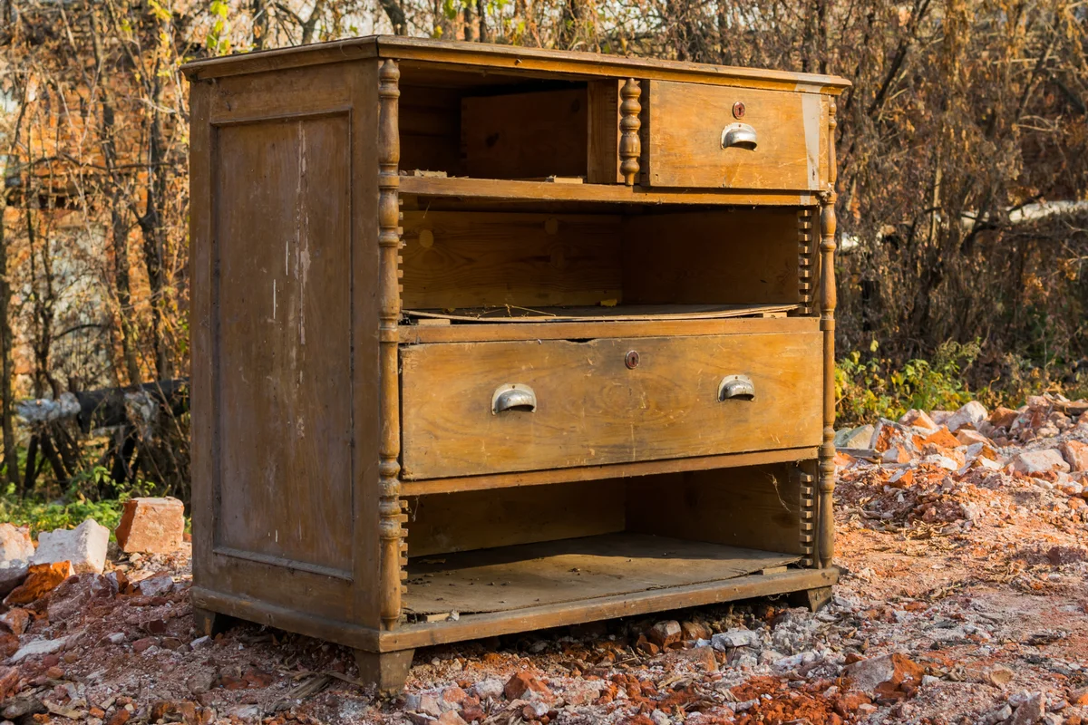 Old, broken dresser thrown in the trash.