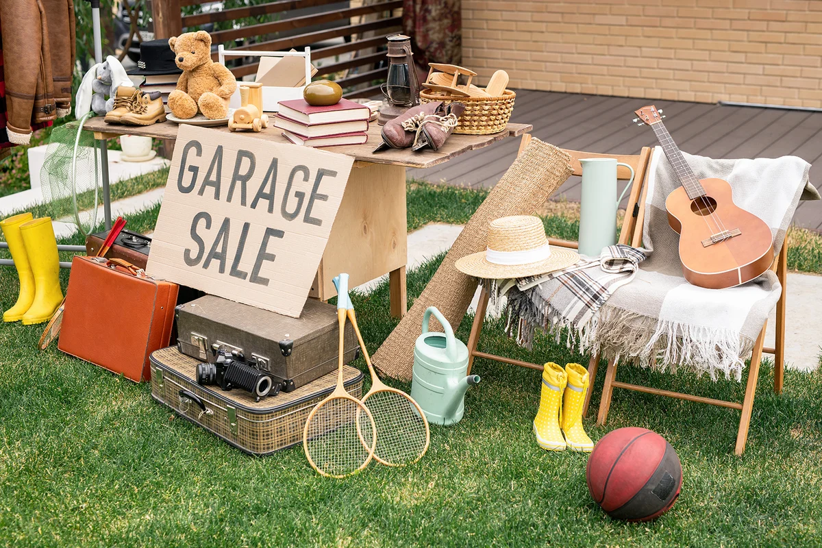 Various things placed on table and chairs in backyard, garage sale