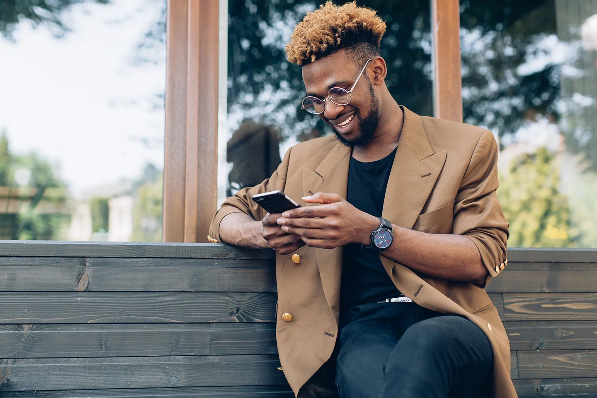 man in jacket and glasses with smartphone texting