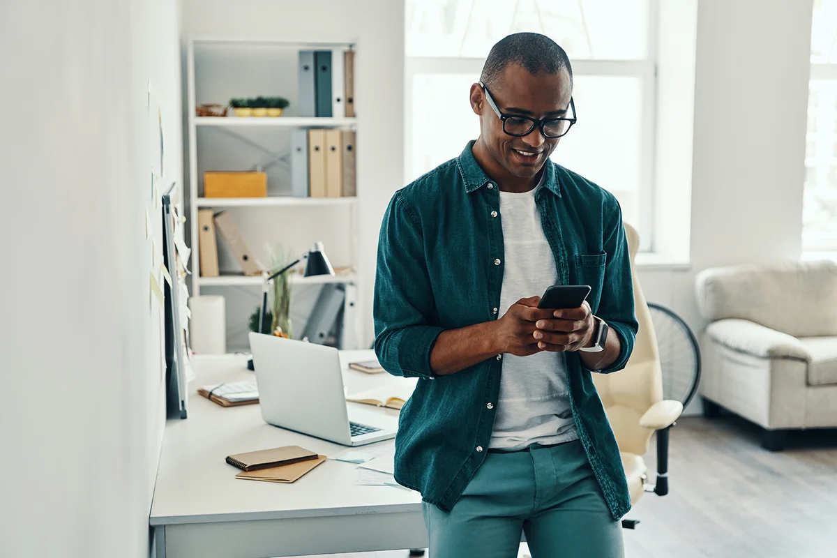 man in shirt using smart phone while standing