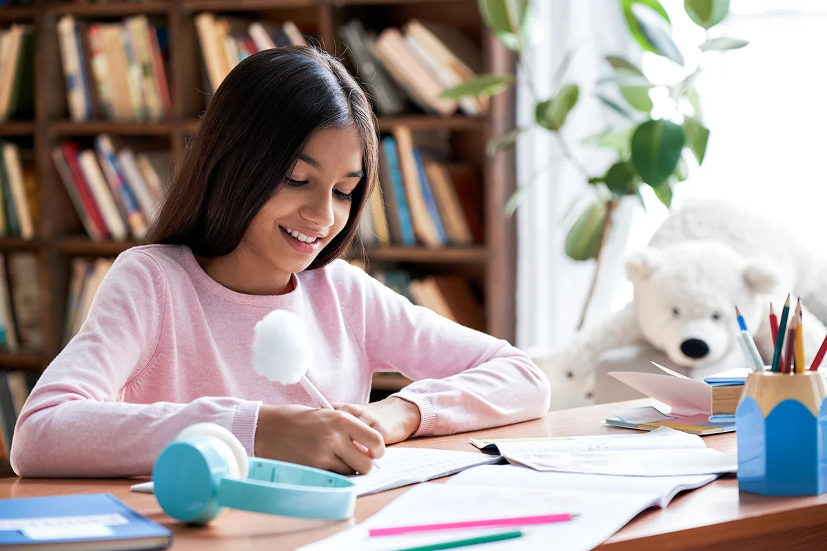 Teen girl studying at home sitting at desk
