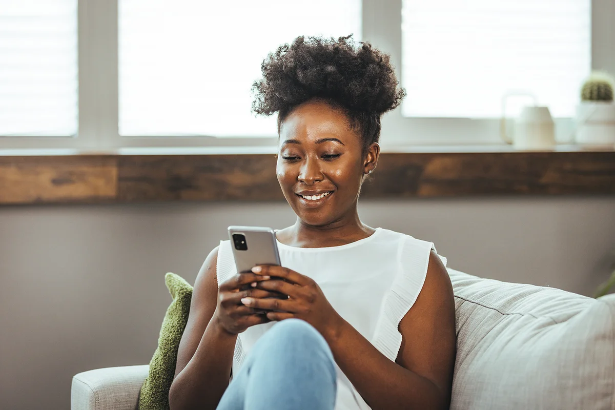 young woman using her cellphone while sitting in the living room