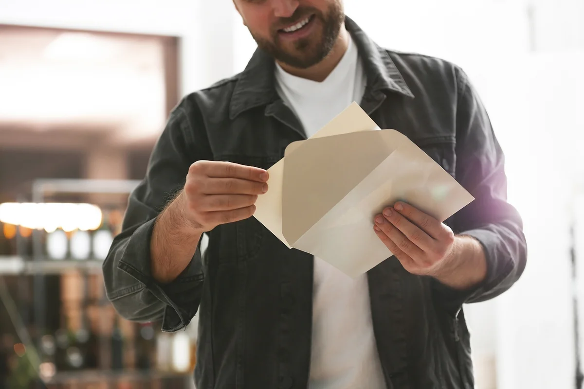 Man holding envelope with greeting card indoors