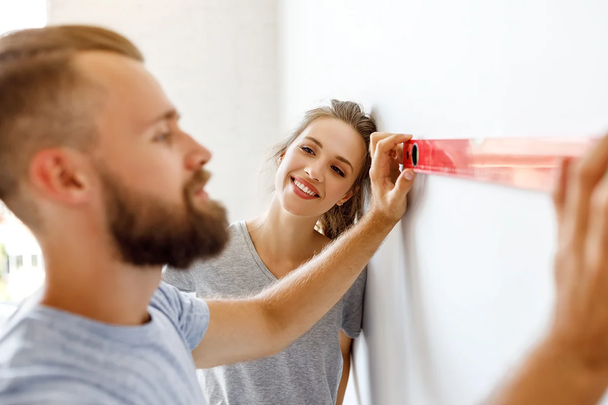 happy couple is repairing and painting the wall at home