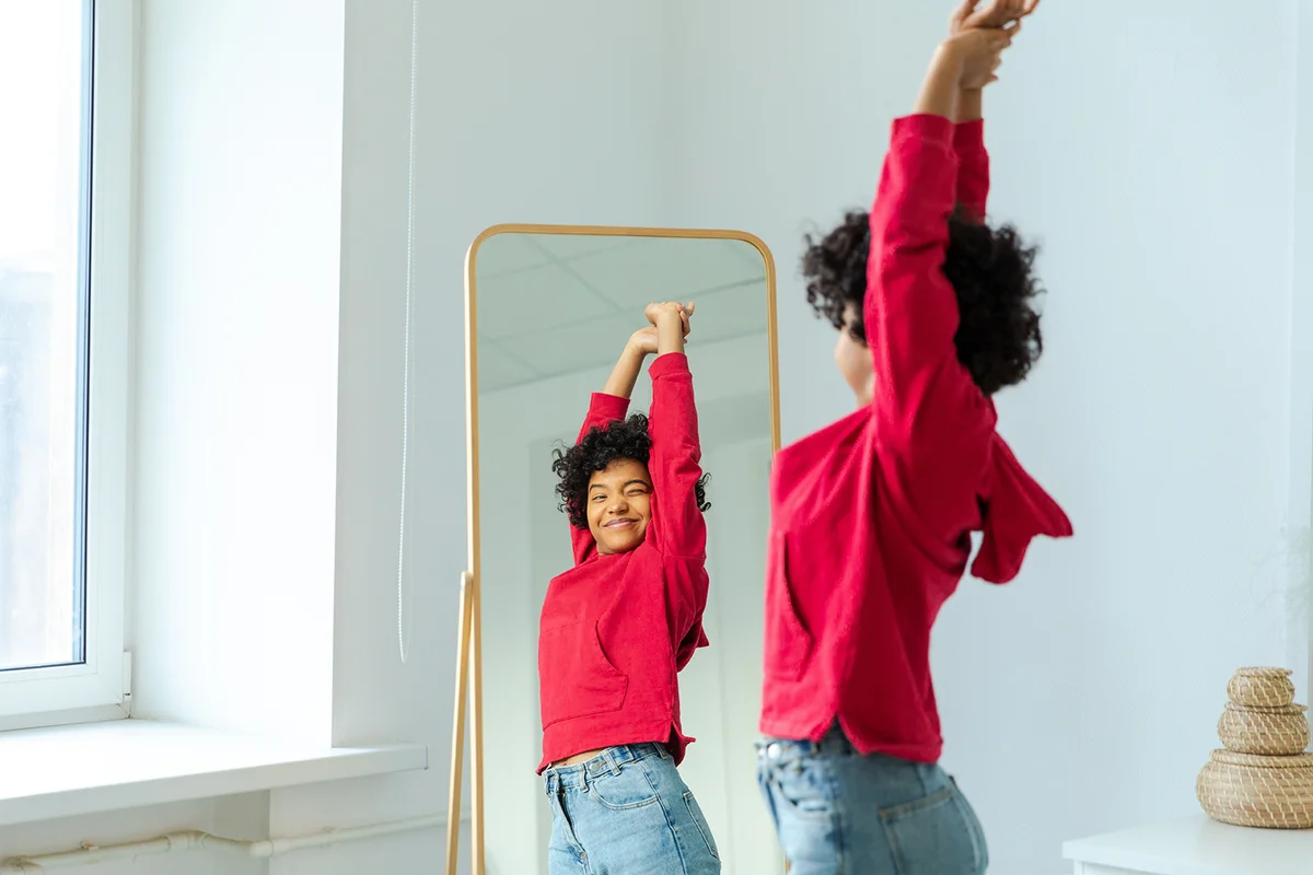 Beautiful young smiling woman dancing enjoying her mirror reflection